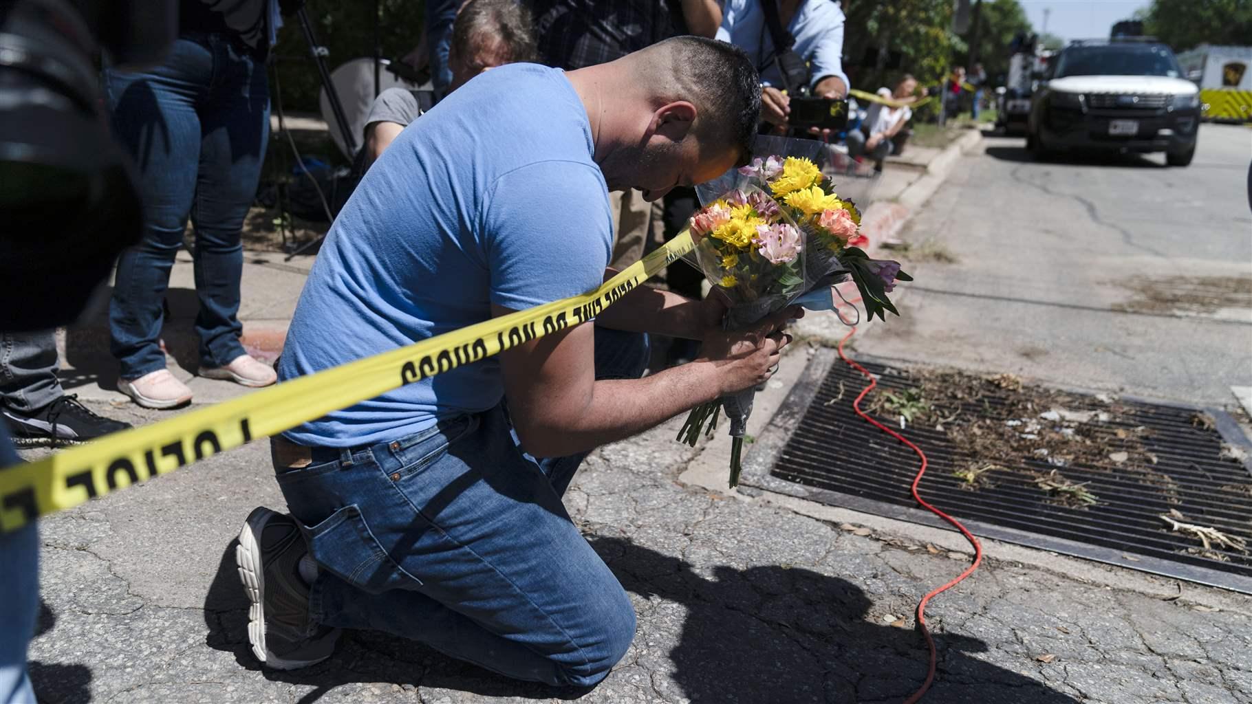 Joseph Avila prays while holding flowers honoring the victims killed in Tuesday’s shooting at Robb Elementary School in Uvalde, Texas, Wednesday, May 25, 2022. Desperation turned to heart-wrenching sorrow for families of grade schoolers killed after an 18-year-old gunman barricaded himself in their Texas classroom and began shooting, killing at least 19 fourth-graders and their two teachers. (AP Photo/Jae C. Hong)