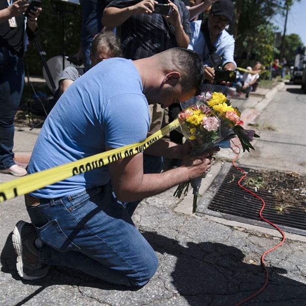 Joseph Avila, left, prays while holding flowers honoring the victims killed in Tuesday’s shooting at Robb Elementary School in Uvalde, Texas, Wednesday, May 25, 2022. Desperation turned to heart-wrenching sorrow for families of grade schoolers killed after an 18-year-old gunman barricaded himself in their Texas classroom and began shooting, killing at least 19 fourth-graders and their two teachers. (AP Photo/Jae C. Hong)