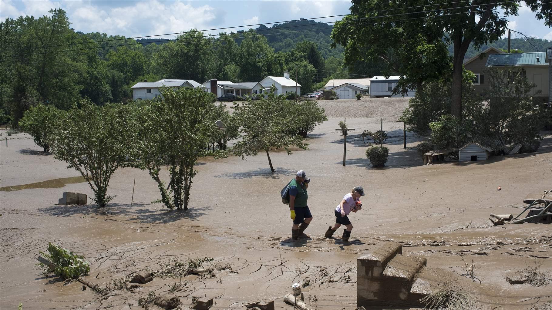 People trudge through the mud left over from the flooding of the Elk River along State Route 119, on June 25, 2016 in Falling Rock, West Virginia. 