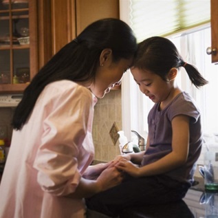 Asian mother comforting daughter in kitchen