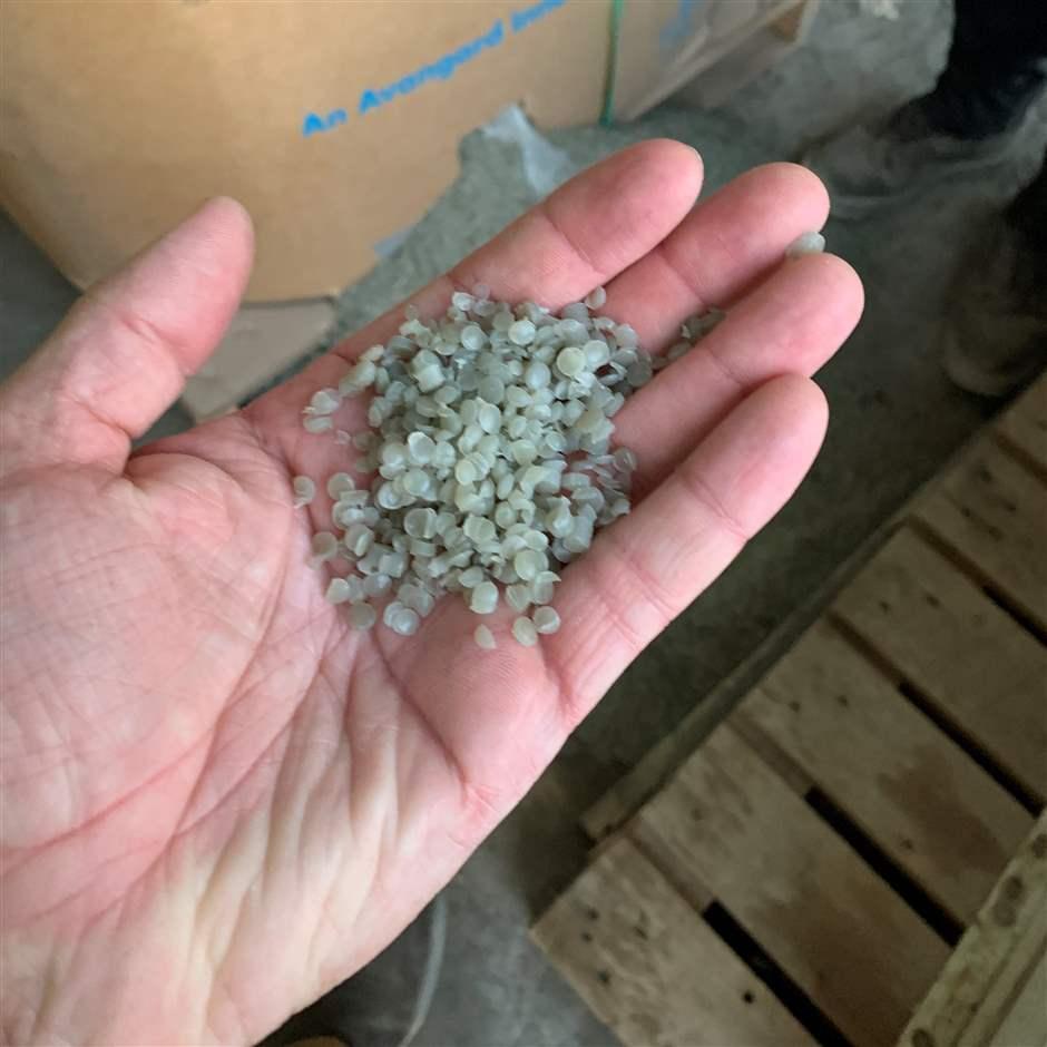 A Missouri Department of Transportation contractor holds plastic pellets before they go into an asphalt mix that gets turned into pavement.
