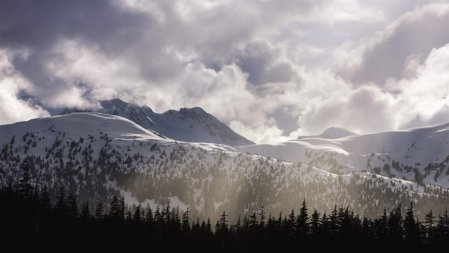 The sun breaks through the clouds over the Chilkat Range in the Tongass National Forest.