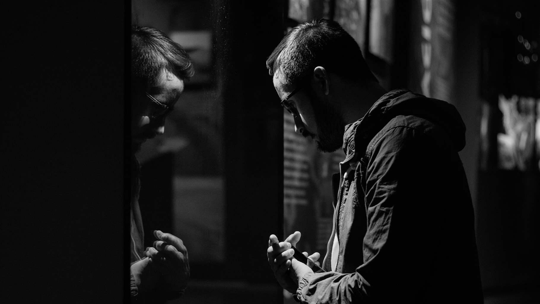 Man looking at his reflection in a somber black and white setting