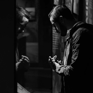 Man looking at his reflection in a somber black and white setting