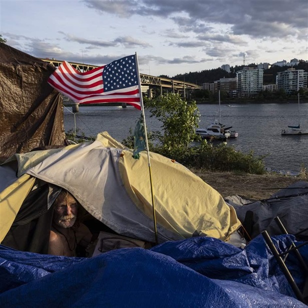 Frank, a homeless man, sits in his tent with a river view in Portland, Ore., on June 5, 2021.