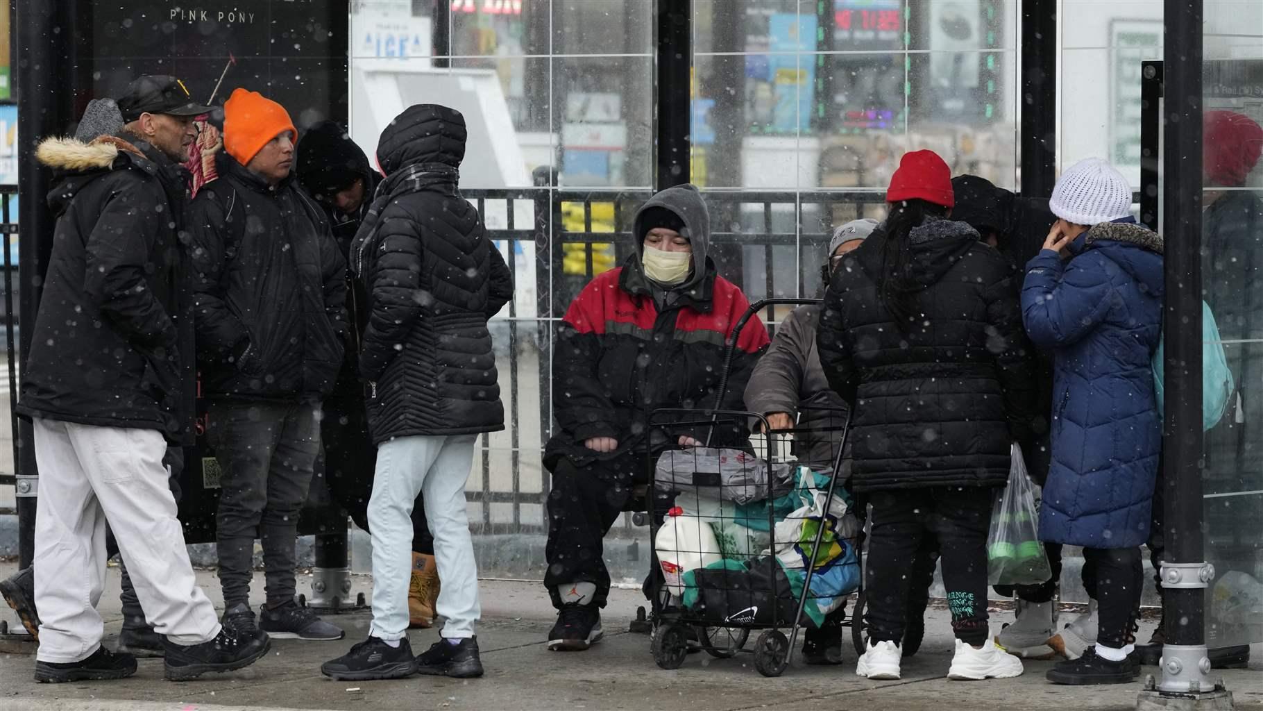 People wait for a bus in Chicago, Thursday, Jan. 5, 2023. (AP Photo/Nam Y. Huh)