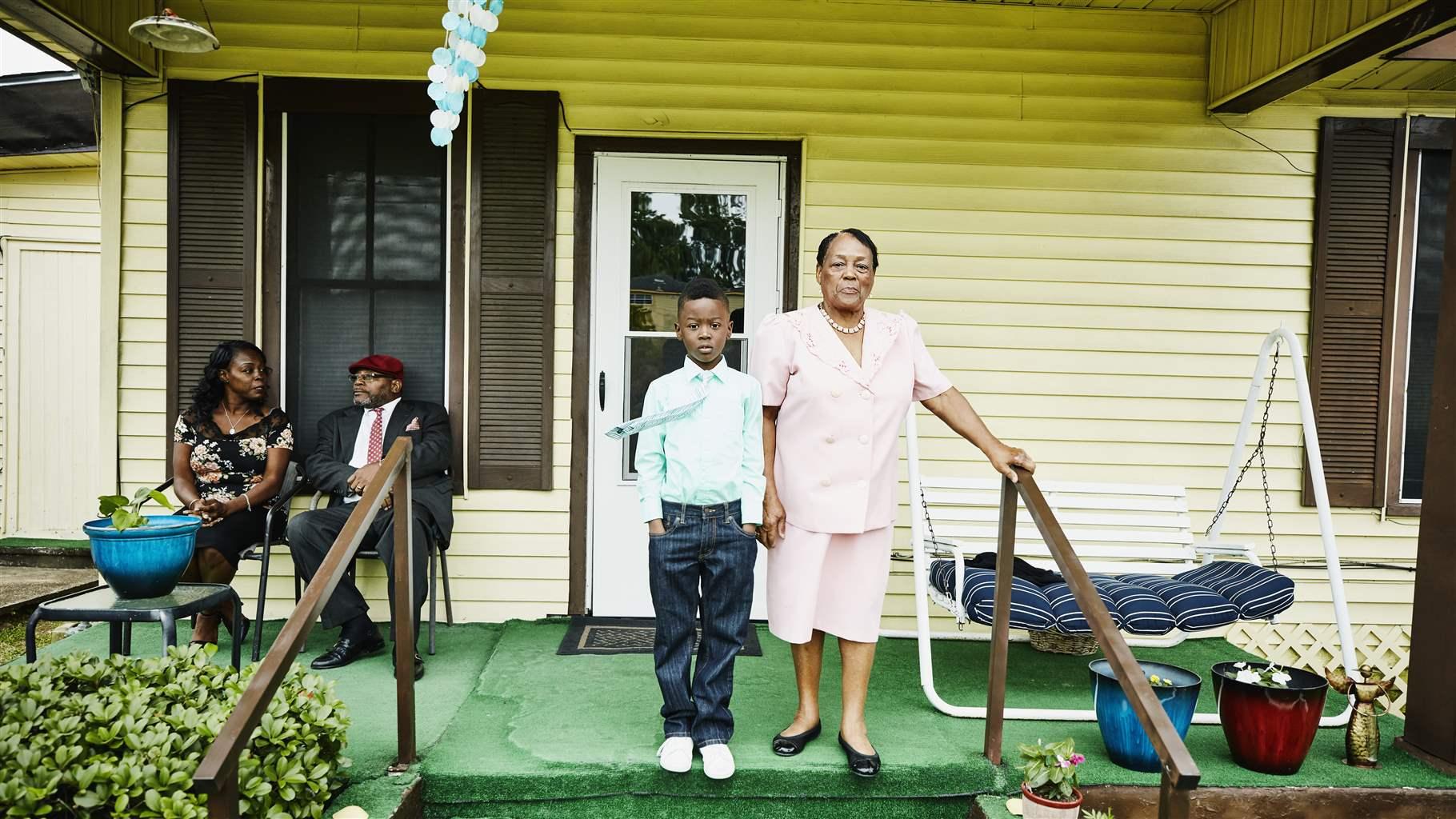 Young boy standing with grandmother on front porch of home