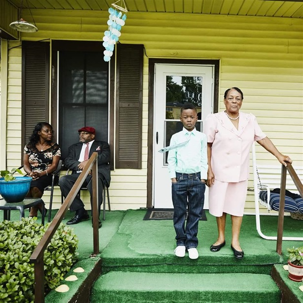 Young boy standing with grandmother on front porch of home