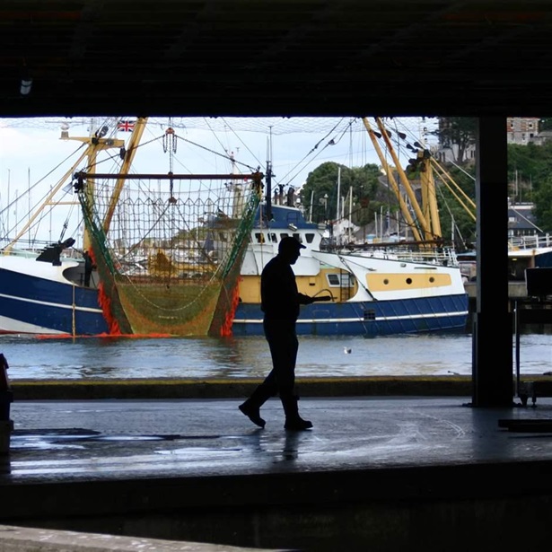 person walking by a fishing boat in a port