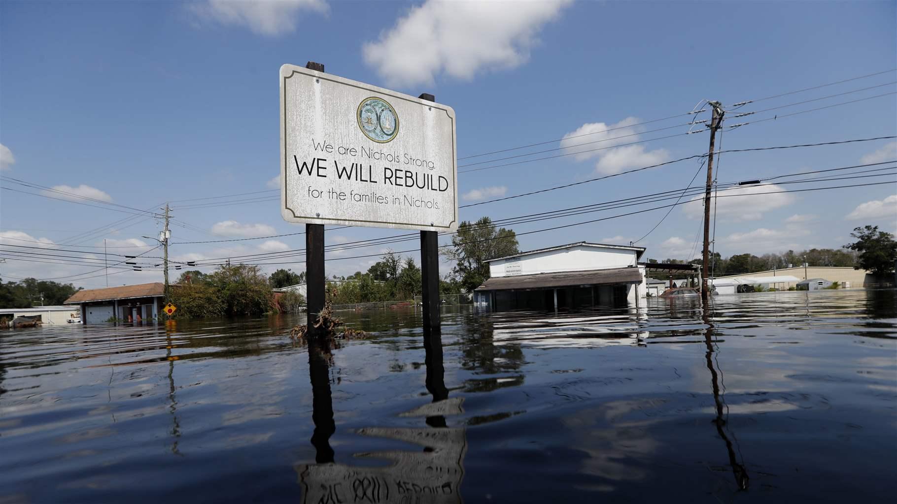 A sign erected in 2016 after flooding from Hurricane Matthew devastated Nichols, South Carolina, was itself nearly overcome by floodwaters in 2018 following Hurricane Florence. 