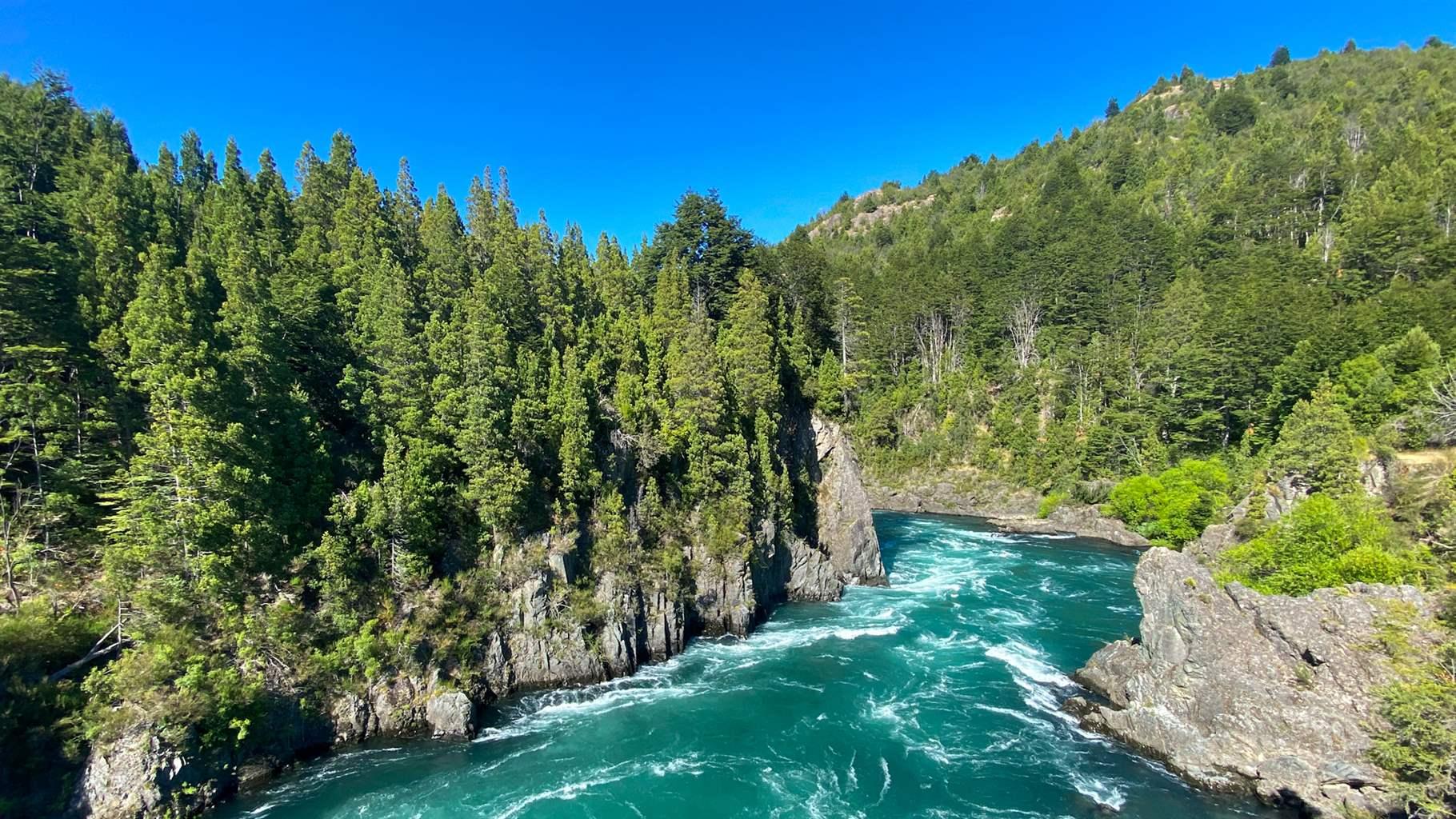Tree-topped rocky outcroppings border the swirling, white-tipped turquoise waters of Chile’s Futaleufú River.