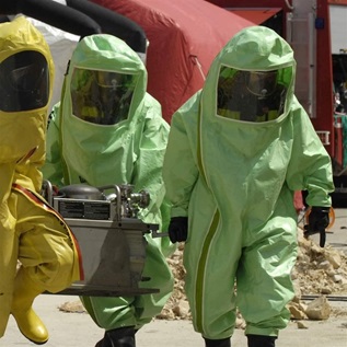 Four decontamination operatives at work in green and yellow