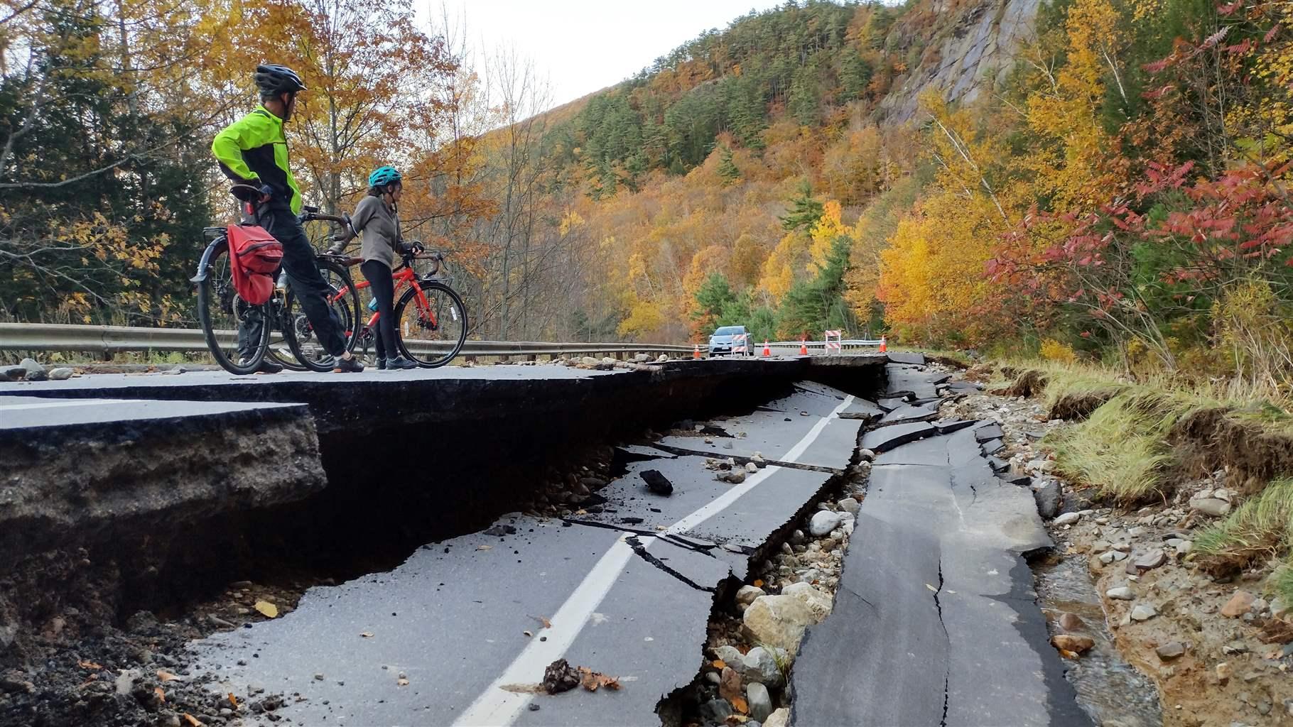 Cyclists in Camden, Maine look at damage to Turnpike Drive from a storm in October 2021 that brought more than 5.5 inches of rain to the region. 