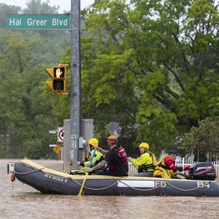 First responders launch a boat along a flooded Hal Greer Boulevard as they go to check on residents in Enslow Park on Friday, May 6, 2022, in Huntington.