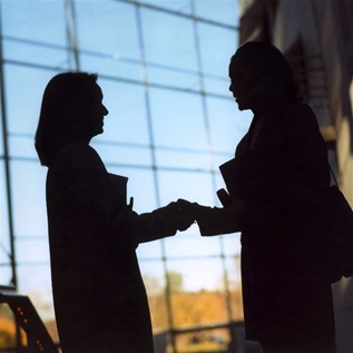 Businesswomen shake hands in silhouette