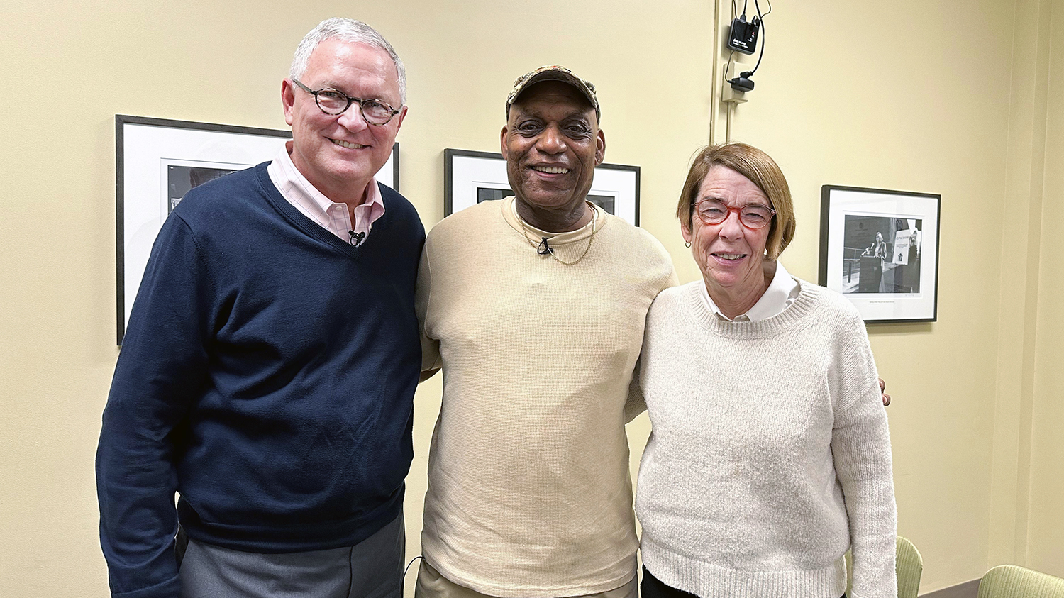 “After the Fact” host Dan LeDuc, in a blue sweater, interviewed Wes Mitchell, who is wearing a tan pullover, and Sister Mary Scullion, wearing a white sweater, in Project HOME’s offices, where the tan walls are decorated with black-and-white photos depicting the organization’s activities over the years. 