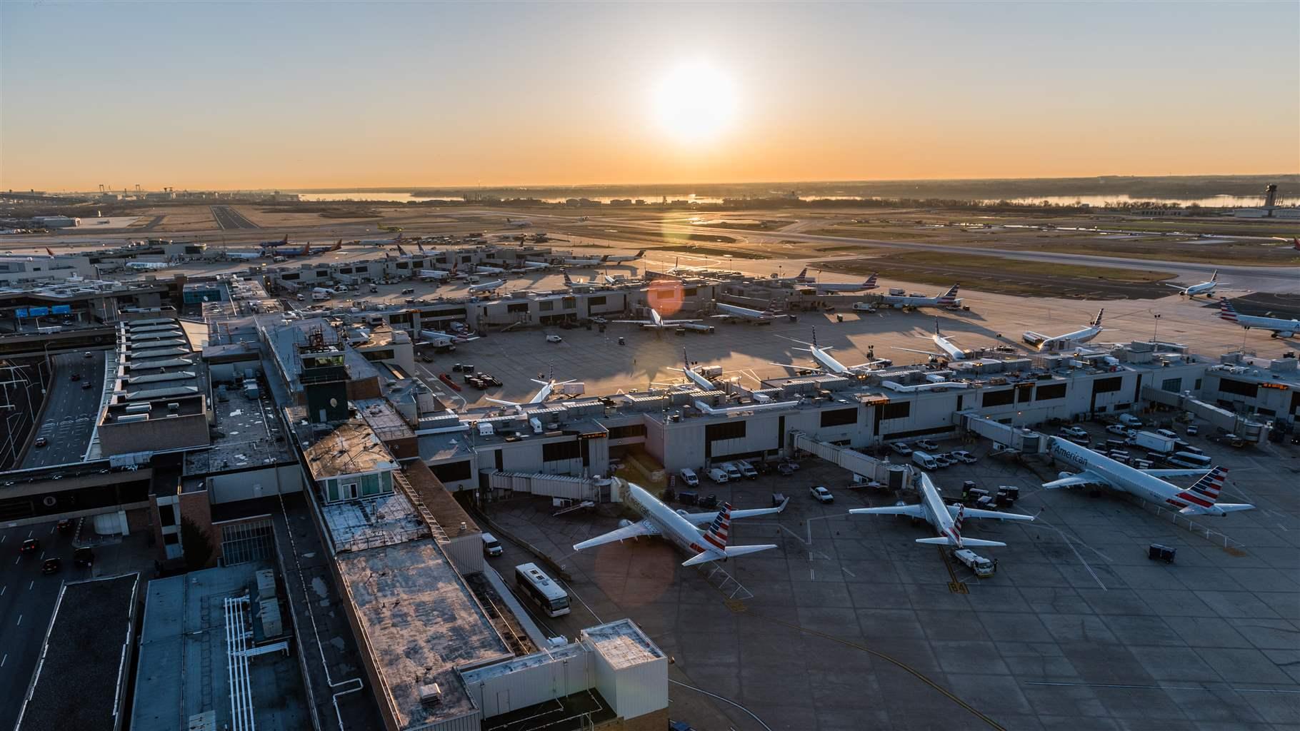 A bird’s-eye view of the city’s main airport, with several airplanes parked at its gates as the sun sits low in the sky. 