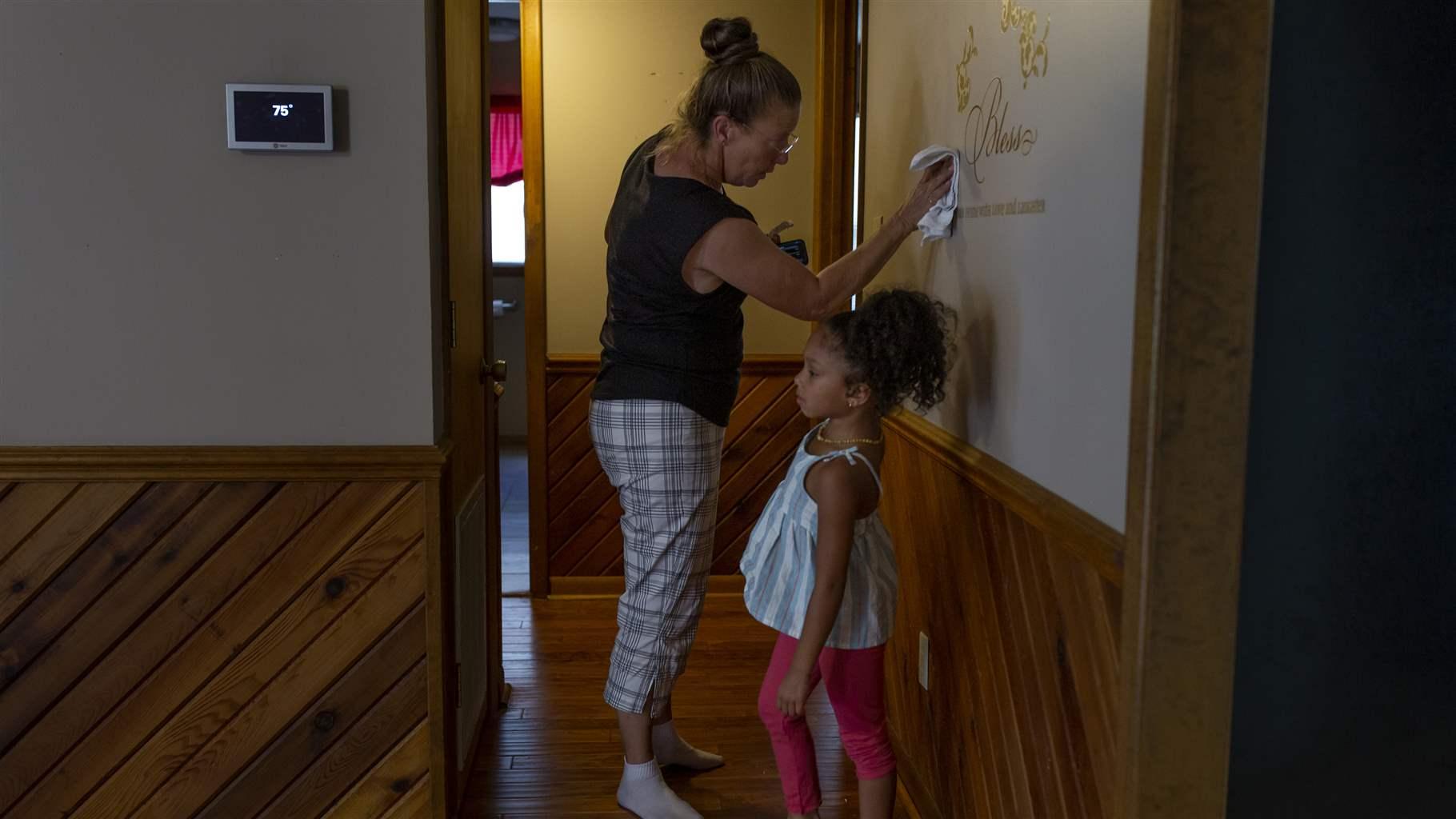 Terri Straka, who participated in a buyout program designed to move Horry County, South Carolina, residents out of flood-prone areas, stencils the wall of her new home on her move-in day, Sept. 19, 2022, with her granddaughter, Sophia. 