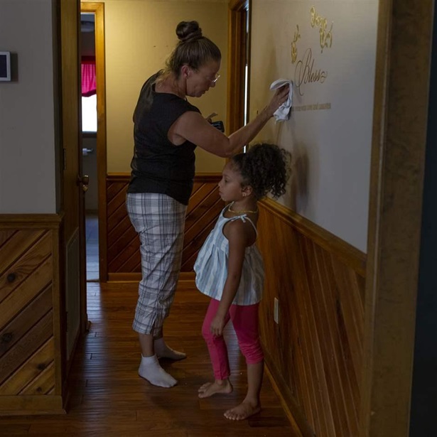 Terri Straka, who participated in a buyout program designed to move Horry County, South Carolina, residents out of flood-prone areas, stencils the wall of her new home on her move-in day, Sept. 19, 2022, with her granddaughter, Sophia. 