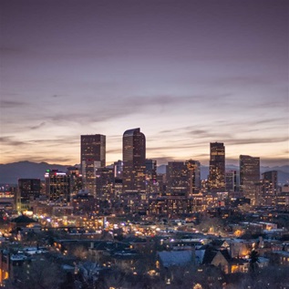 Elevated perspective of the Denver metro area and downtown skyline with The Rocky Mountains as a backdrop.