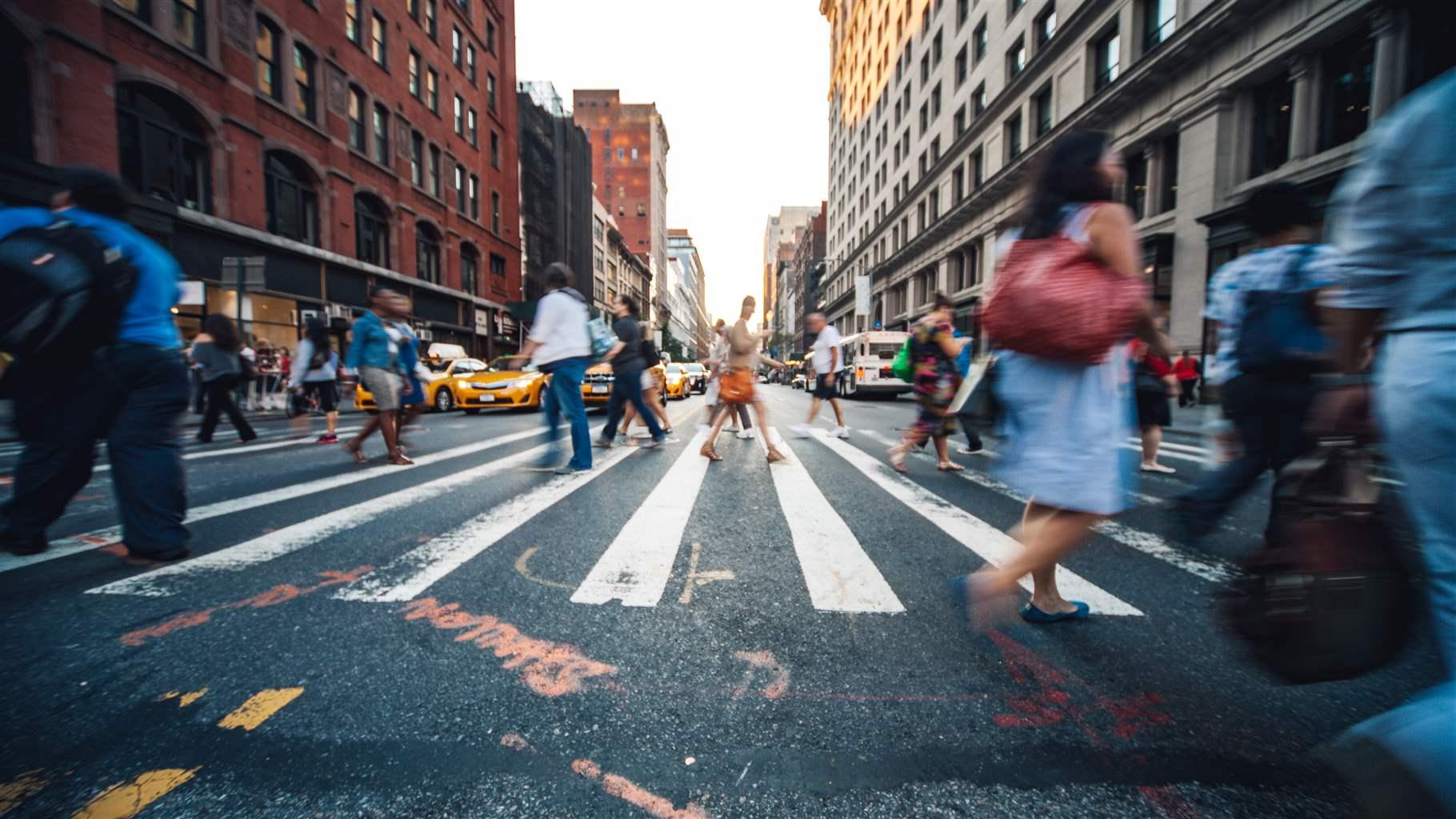  aCrowd of people crossing the street in Midtown Manhattan.