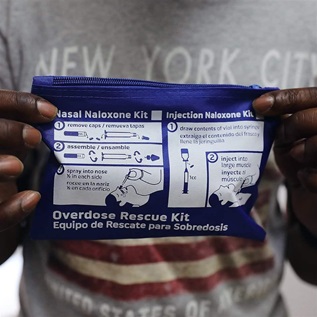 A man holds up an overdose rescue kit.