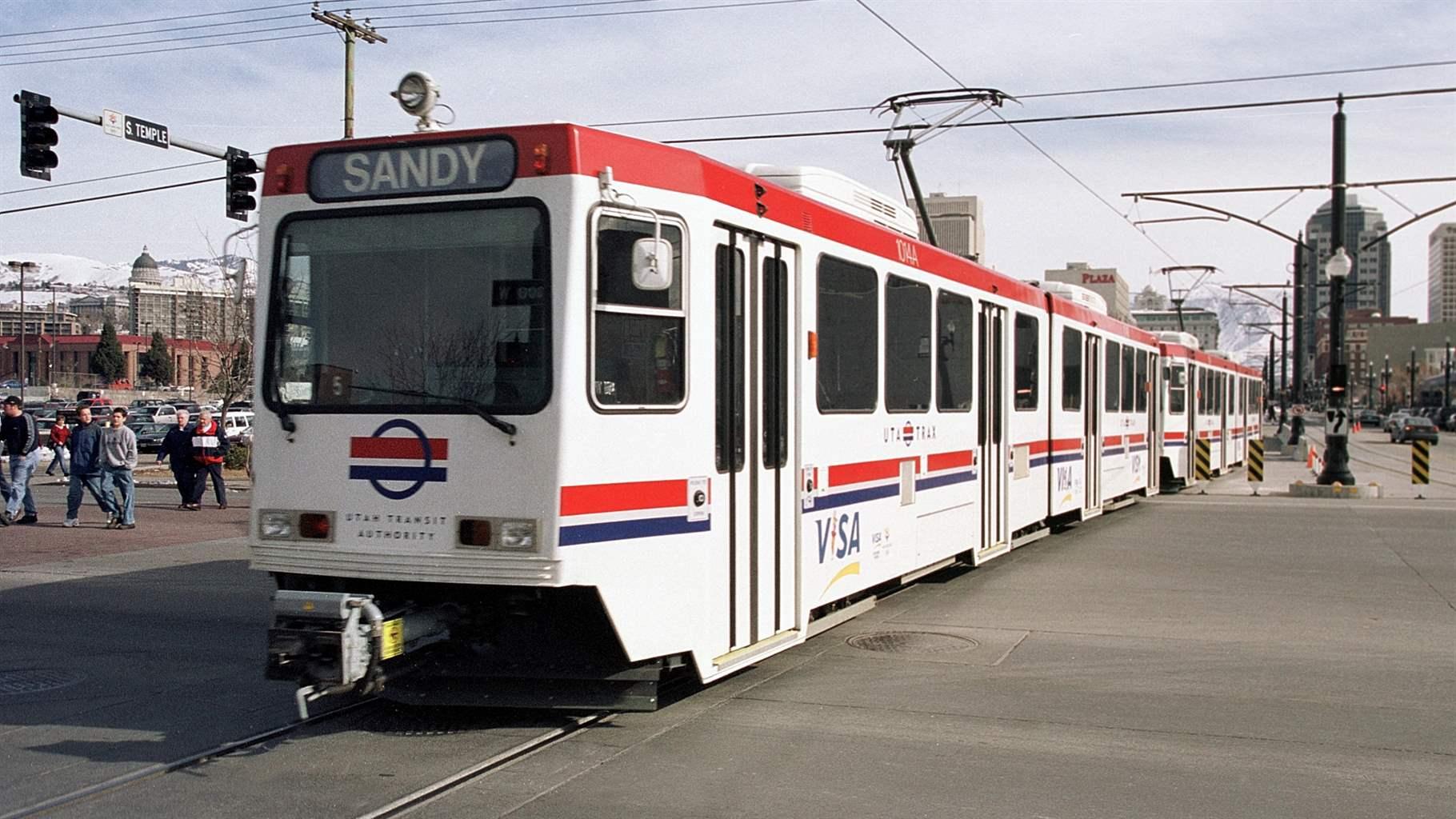 A large white light rail train moving through Salt Lake City.
