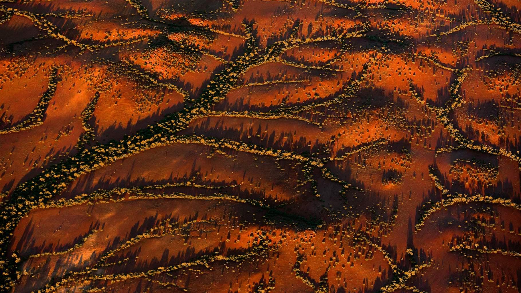 An aerial photograph shows a gully system in Western Australia, with vegetation growing in the gullies and deep red-and-brown dirt.