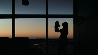 Silhouette of mother and newborn in hospital room at sunset