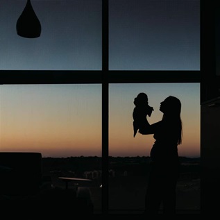 Silhouette of mother and newborn in hospital room at sunset