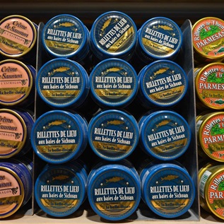 Three different canned tuna brands are pictured close-up on a market shelf.